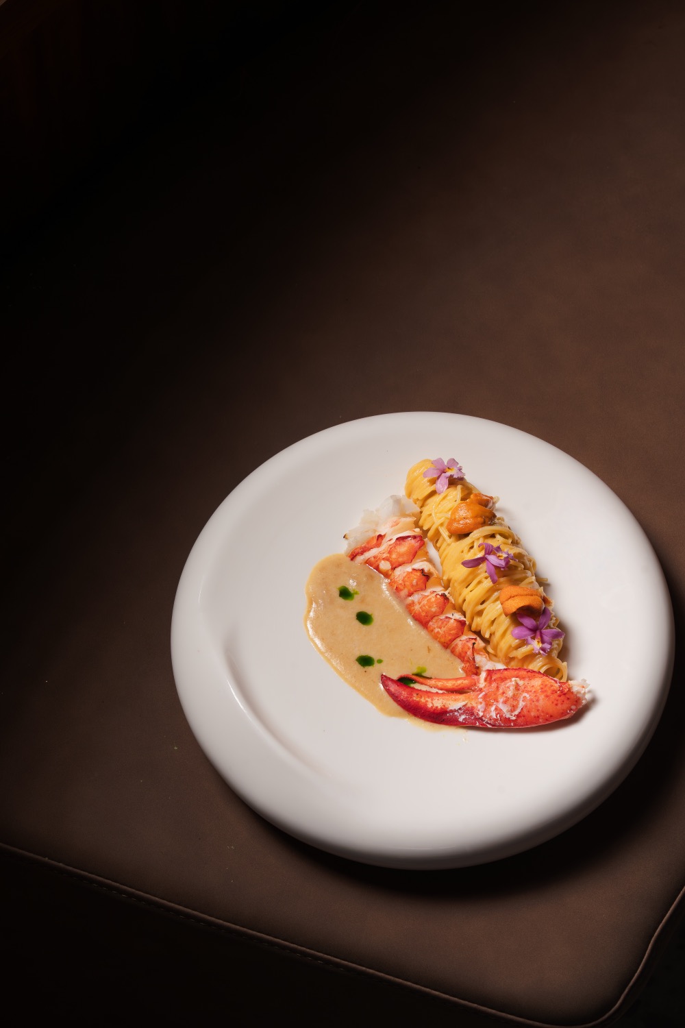 Lobster Uni Pasta: lobster tail and claw beside pasta topped with uni